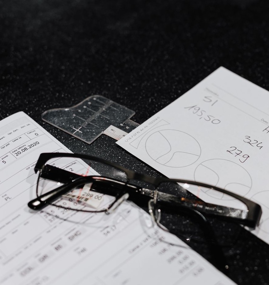 An optician's worksheet with handwritten lens values, lens-shape diagrams and a pair of glasses
