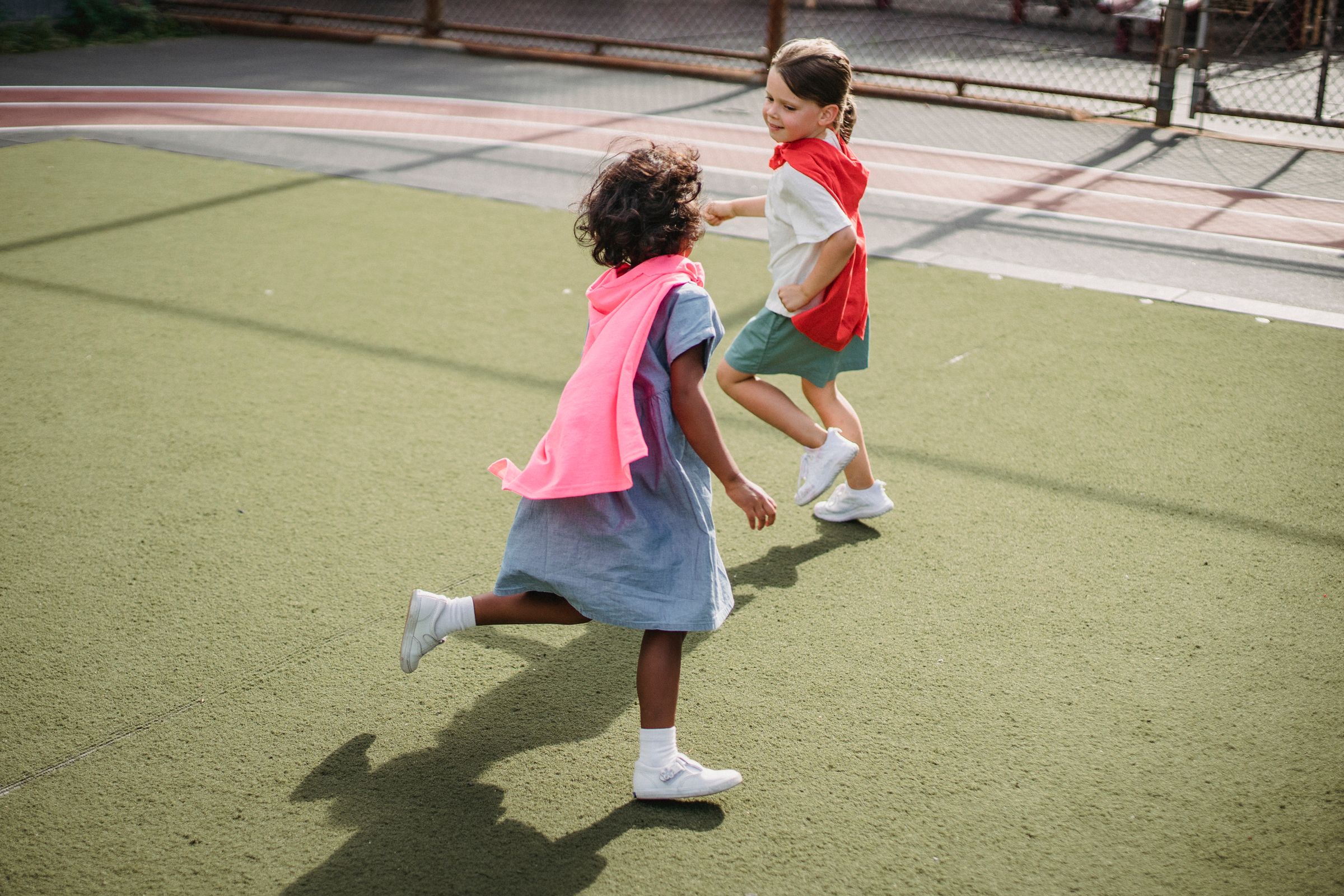 Two children running outside in bright daylight